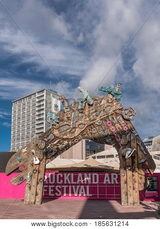 Auckland New Zealand - March 4 2017: Wooden colorful festive gate at Auckland Art Festival on Aotea Square under blue sky with white clouds. Combination of Maori symbols masks and art objects.