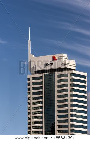 Auckland New Zealand - March 4 2017: White stone and black window office building of PricewaterhouseCoopers the auditing company isolated against blue sky.