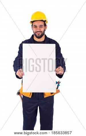 Handsome beard young worker smiling and holding a blankboard guy wearing workwear and yellow helmet with belt equipment isolated on white background