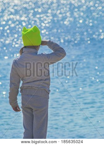 The child in sports clothes looking into the ocean