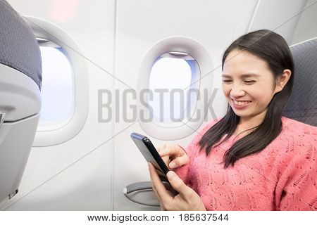 Middle aged woman smie and use phone in the airplane