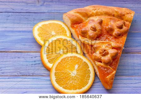 A piece of cake with orange confiture on a wooden table. Delicious dessert.