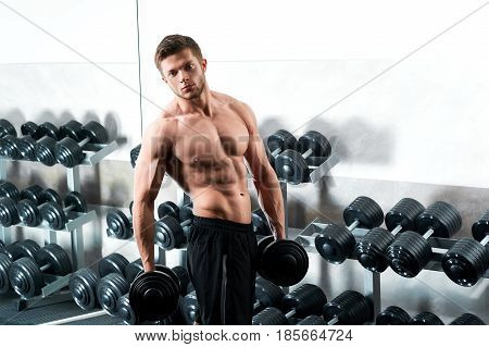 Fitness shot of a muscular young man working out with heavy dumbbell at the gym sport people lifestyle motivation sportsman health muscles sexy shirtless guy concept.