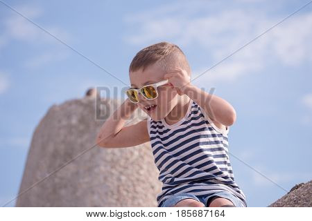 Surprised little boy with sunglasses and sailor stripes shirt in summer