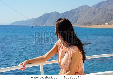 Young girl on a boat tropical beach enjoying the beautiful sunrise view in the morning. Beautiful Sharm El Sheikh Egypt coastline. Red sea beach resort.