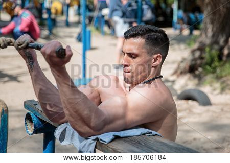 A hard-working guy is doing sports exercises in the park