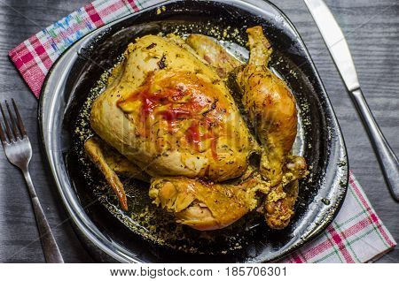 Baked in the oven chicken on the table with the cutlery