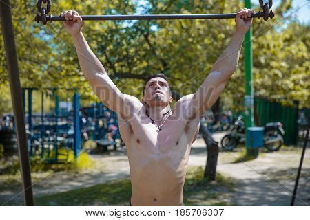 A hard-working guy is doing sports exercises in the park