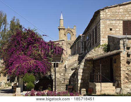 Old house in a church area with a blossom bouganvillea and a blue sky in background picture from the North of Cyprus.