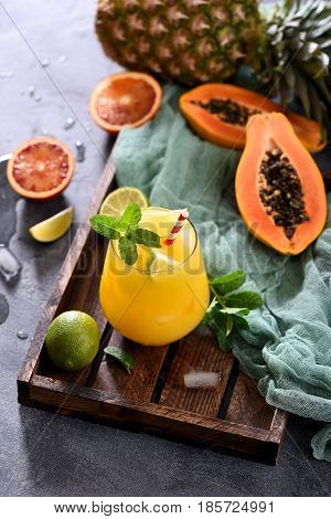 Fresh cold drink cocktail or lemonade with tropical fruits papaya pineapple lime juicy summer beverage