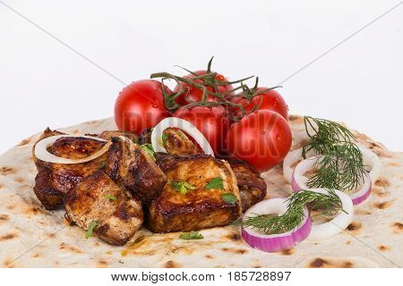 pieces of roasted meat with vegetables. grilled meat with tomatoes and greens on a pita.