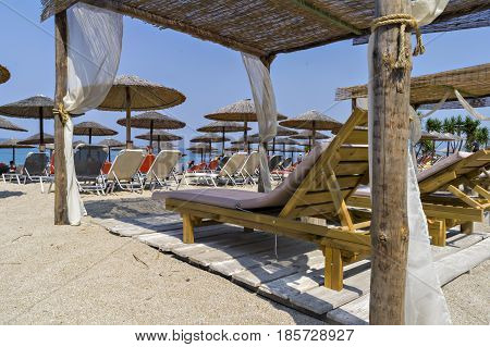 Beautiful Ionian sandy resort beach in Greece with sunbeds and sunshades. Vacation destination. Public beach