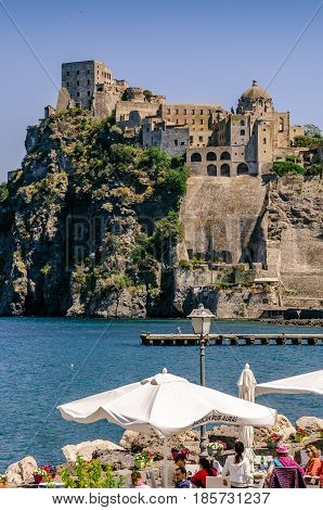 Iaschia March 2017, Italy: Restaurants on the sea in Ischia Ponte with tourists who dine at the sight of the Aragonese Castle, a fortification that rises on the eastern side of Ischia Island.