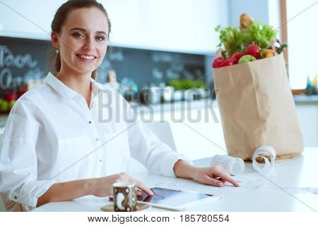 Young woman planning expenses and paying bills on her kitchen