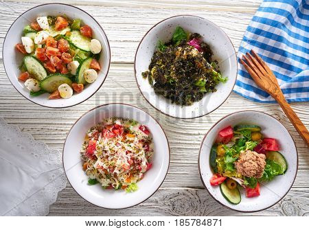 four salad mix bowls healthy food on white wood table