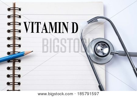 Stethoscope on notebook and pencil with VITAMIN D words as medical concept.