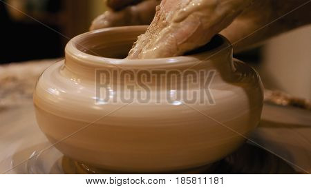 Potter is making clay pot bowl or vase ceramics porcelain on the potter's wheel. Creating pottery art and handicraft modelling creation.