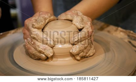 Potter is making clay pot bowl or vase ceramics porcelain on the potter's wheel. Creating pottery art and handicraft modelling creation.