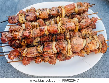 Shish kebabs on skeweres cooked on a charcoal gril laid out on a platel
