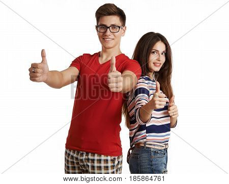 Portrait of happy smiling friends showing thumbs up posing in studio over white background. Young pretty Caucasian couple gesturing "ok".
