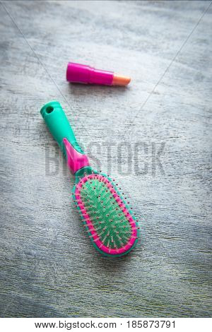 Green and pink hairbrush lipstick on a light wooden background