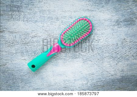 Green and pink hairbrush on a light wooden background