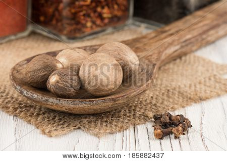 Nutmeg in a wooden spoon on old wooden table. Selective focus.