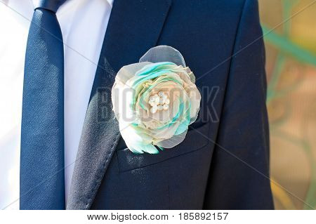 White Boutonniere Decorated With Mint Feathers Pinned To Blue Jacket