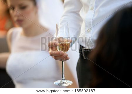 Man in white shirt holds a champagne flute standing behind a bride