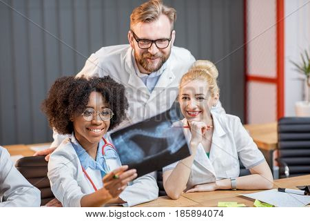 Multi ethnic group of medical students in uniform looking on the x-ray sitting at the desk in the modern classroom