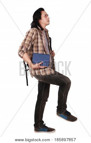 Photo image portrait of a cute young Asian male student with long hair looking up and stepping forward while holding books isolated on white