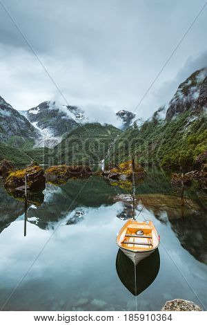 Fishing boat on a still lake in Norway and high mountains in background. Bondhusvatnet