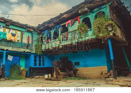 Vashisht. India. April 21 2017. Traditional house for the Himalayan region with a balcony and a cow from below
