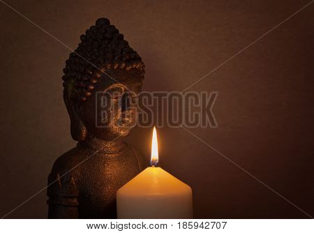 Statue of a holy Buddha in the light of a candle on a wooden background