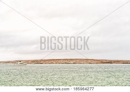 LANGEBAAN SOUTH AFRICA - MARCH 31 2017: A catamaran on the Langebaan lagoon with thousands of cormorants on Schaapen Island in the back