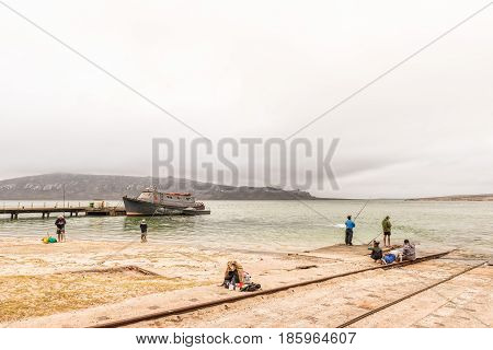 LANGEBAAN SOUTH AFRICA - MARCH 31 2017: A boat anchored at a pier and anglers at a boat launching site at Langebaan on the Atlantic Coast of the Western Cape Province