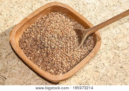 Old wheat species - grain-like triangular buckwheat seeds - in a rustic wooden shell with a wooden spoon. 
