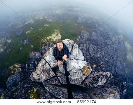 Male tourist man sitting jumping on a mountain on a  sea background. Teriberka, Murmansk region, the Kola Peninsula, Russia. action cam
