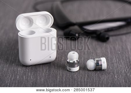 Wireless Cordless Bluetooth Earbuds With Chargeable Case On A Background Of Neck Band Type Earphone