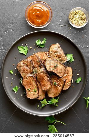 Sliced Roasted Beef Liver On Plate Over Black Stone Background. Cooked Liver(offal) From Beef. Top V