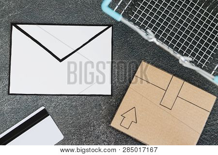 Shopping Cart With Cardboard Parcel Email Envelope And Payment Card On Concrete Desk, Concept Of Shi