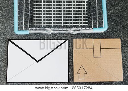 Shopping Cart With Cardboard Parcel And Email Envelope On Concrete Desk, Concept Of Shipping And Tra
