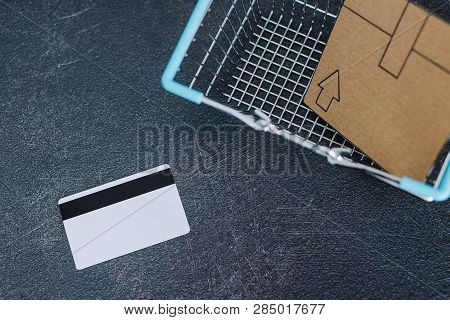 Shopping Cart With Cardboard Parcel Email Envelope And Payment Card On Concrete Desk, Concept Of Shi