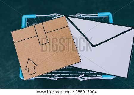 Shopping Cart With Cardboard Parcel And Email Envelope On Concrete Desk, Concept Of Shipping And Tra