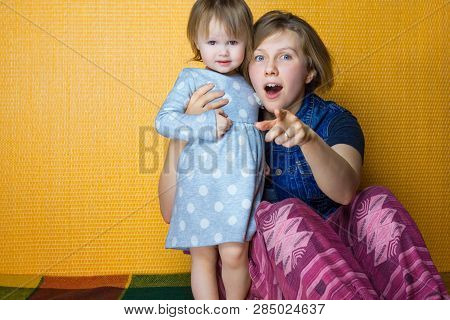 Portrait Of Mother Hugging Toddler Daughter. Pretty, Amazed Girl Look To Camera. Woman, Person Point