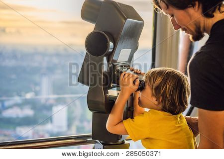 Dad And Son Are Looking At Kuala Lumpur Cityscape. Use Binoculars. Panoramic View Of Kuala Lumpur Ci