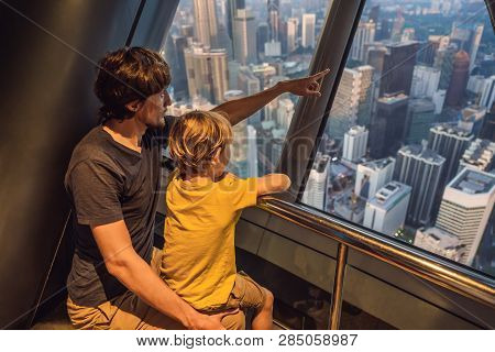 Dad And Son Are Looking At Kuala Lumpur Cityscape. Panoramic View Of Kuala Lumpur City Skyline Eveni