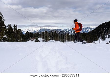 Man In Orange Jacket Snowshoeing On Scheibelalm In Holiday Resort Hohentauern With Panoramic View To