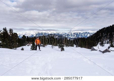 Man In Orange Jacket Snowshoeing On Scheibelalm In Holiday Resort Hohentauern With Panoramic View To