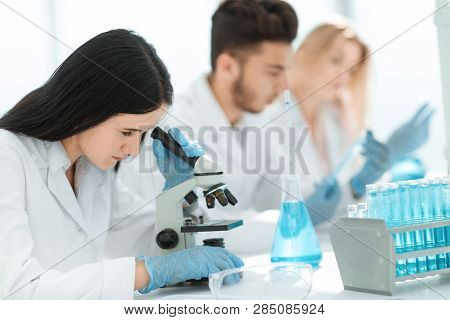 Close Up.female Scientist Uses A Microscope To Analyze The Liquid.